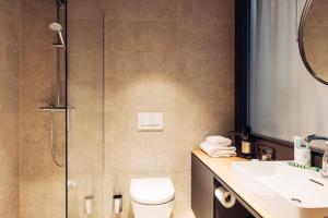 a bathroom with a shower and a toilet and a sink at harry's home hotel & apartments in Steyr