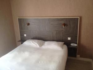 uma cama com lençóis brancos e almofadas num quarto em Hotel du Commerce em Cholet