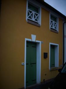 een geel gebouw met groene deuren en ramen bij Appartamento Sonia in Thiene