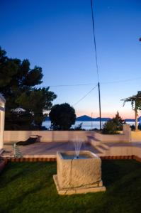 a fountain in the grass with the ocean in the background at Apartment & Rooms Villa Katarina in Slano