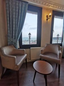 a living room with two chairs and a table and windows at Agora Boutique Hotel & Bistro in Istanbul