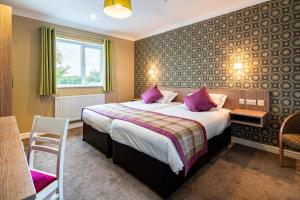 a hotel room with a large bed with purple pillows at White House in St Asaph