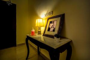 uma mesa com uma lâmpada e uma imagem e uma lâmpada em The Umaid Vilas Royal Heritage Haveli em Jaipur