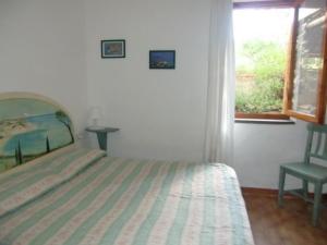 a bedroom with a bed and a chair and a window at Agenzia Ammiraglio in Giglio Porto