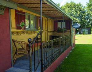 una pequeña casa amarilla con porche con silla en Le Riolet, en Marsac-en-Livradois