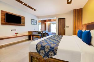 a hotel room with a bed and a television at Club Mahindra Netrang in Netrang