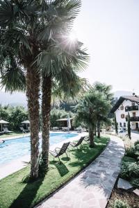 a pool with palm trees next to a resort at Waidmannhof in Merano