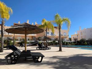 - une terrasse avec des chaises et un parasol à côté de la piscine dans l'établissement Apartamento VerdeMar Cabanas Gardens by Your Home Algarve, à Cabanas de Tavira