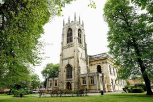 eine alte Kirche mit einem hohen Turm in einem Park in der Unterkunft Gainsborough Hotel in Gainsborough