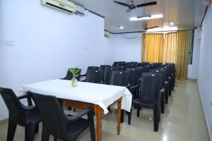 a dining room with a white table and black chairs at Ramanilayam Tourist Home in Ambalapulai