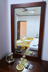 a mirror on a table with a bed in a room at Ramanilayam Tourist Home in Ambalapulai