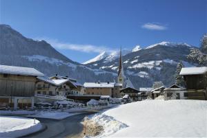 uma aldeia coberta de neve com uma igreja nas montanhas em All Inclusive Hotel Bachmayerhof em Uderns
