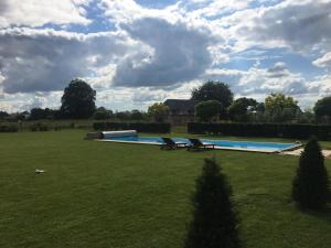 una piscina en un campo de césped con una casa en ClosSaintJoseph - Option Repas - Piscine chauffée Proximité Yvetot, en Sainte-Marie-des-Champs