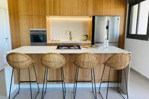 a kitchen with a counter with three bar stools at 4 Bedroom Beach Apartment with Stunning Views in Nahariyya