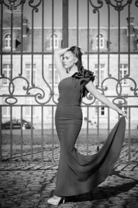 a woman in a dress leaning against a fence at Château de Plessier-Roza in Le Plessier-Rozainvillers