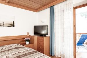 a bedroom with a bed and a tv and a window at Haus Bergfrieden Seiser Alm in Siusi