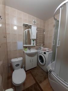 a bathroom with a toilet sink and a washing machine at Двокімнатна in Shepetivka