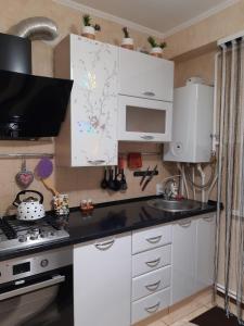 a kitchen with white cabinets and a sink and a stove at Двокімнатна in Shepetivka