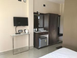 a hotel room with a bed and a tv and a room at Samriddhi Banquet Garden & Resorts in Baharampur