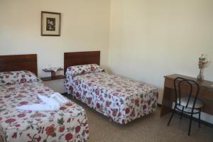 um quarto de hotel com duas camas e uma secretária e um gato branco deitado em Hostal Torre Mar em Salou