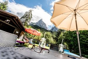 a table with glasses and an umbrella on a patio at Haus Bergfrieden Seiser Alm in Siusi