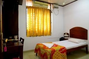 a bedroom with a bed and a desk and a window at Ramanilayam Tourist Home in Ambalapulai