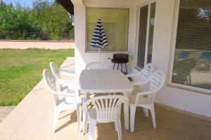 - une table et des chaises blanches sur une terrasse couverte dans l'établissement Вили Брендън и Дезмънд - до Балчик - Brendon and Desmond Villas - near Balchik, à Sokolovo