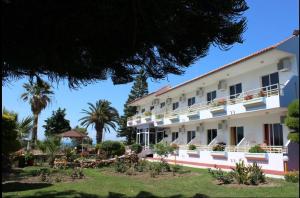 a large white building with palm trees in the background at Asterias Bay-Theologos in Theologos