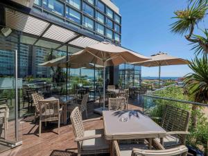 Un patio al aire libre con mesas, sillas y sombrillas. en Pullman Vina del Mar San Martin, en Viña del Mar