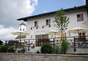 a building with tables and umbrellas in front of it at Gasthaus - Hotel FUCHS in Mauth