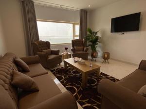 a living room with a couch and chairs and a tv at نسمة كان للشقق المخدومة in Dammam