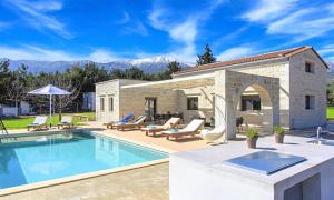 einen Pool mit Stühlen und ein Haus in der Unterkunft Orientem Villa Heated Pool in Georgioupoli
