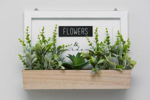 a framed picture of flowers and plants in a wooden box at Stylish & Modern Apartments Praga in Warsaw