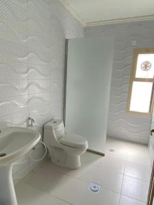 a white bathroom with a toilet and a sink at نسمة كان للشقق المخدومة in Dammam