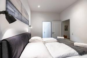 a white bedroom with a large bed with white pillows at Modern apartment next to subway station in Vienna