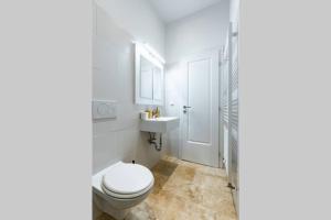 a white bathroom with a toilet and a sink at Modern apartment next to subway station in Vienna