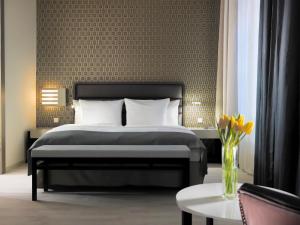 ein Schlafzimmer mit einem Bett und einer Vase aus Blumen in der Unterkunft H10 Ku'damm Lofts in Berlin