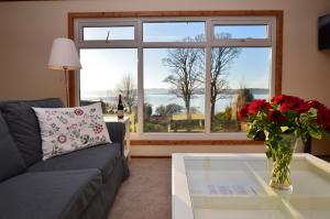 a living room with a couch and a glass table with a vase of roses at Scallopshell Lodge in Otter Ferry