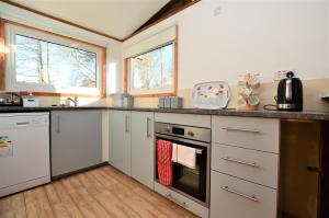 a kitchen with white cabinets and a stove top oven at Scallopshell Lodge in Otter Ferry