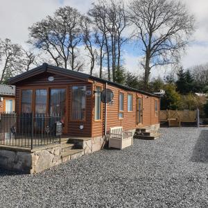 una gran cabaña de madera en un aparcamiento de grava en Deer lodge, en Auchterarder