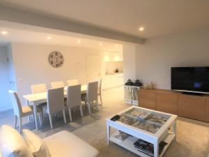 Una sala de estar con una mesa de comedor y un televisor. en De Tureluur, en Cadzand
