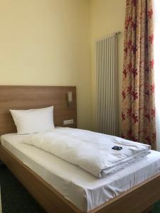 um quarto com uma cama com lençóis brancos e uma janela em Gasthof zum Bären em Bühlertann