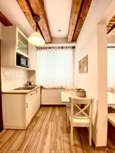 a kitchen with white cabinets and a table and a dining room at CERO Brasov in Braşov