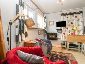a living room with a red couch and a fireplace at Tiny Willow in Blandford Forum