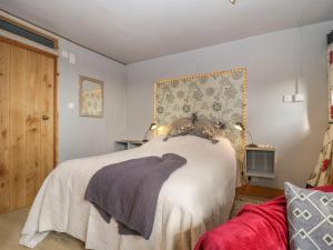 um quarto com uma cama com um cobertor branco em Tiny Willow em Blandford Forum