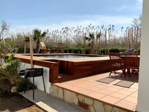 een patio met een zwembad en stoelen en een tafel bij Villas Empúries, Garden & Private Pool in Sant Martí d’Empúries
