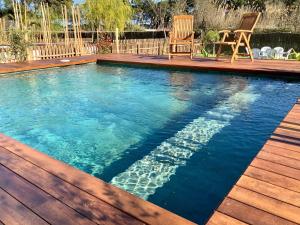 a swimming pool with a deck and chairs in it at Villas Empúries, Garden & Private Pool in Sant Martí d’Empúries