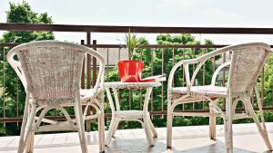 three chairs and a red vase on a balcony at B&B Mariclà in Verona