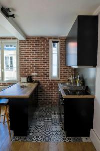 a kitchen with black cabinets and a brick wall at Appart Cosy entre vieux port et marché central in La Rochelle +17 photos