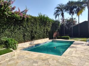 a swimming pool in a yard with a hedge at LM HOTEL ARAÇATUBA in Araçatuba